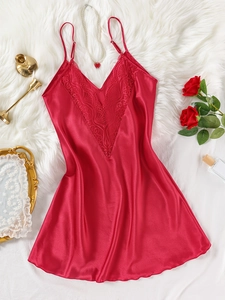 Détail de nuisette en satin rouge avec dentelle col en V sur fond en peluche blanc