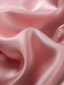Vue rapprochée du tissu en satin de soie rose élégant montrant la texture et le drapé