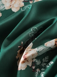 Dettaglio del raso di seta con stampa floreale verde smeraldo e lucentezza setosa