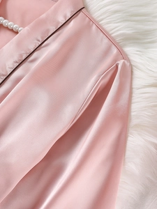 Détail d'un peignoir en satin rose avec liseré contrasté sombre et texture soyeuse