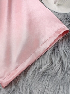 Détail de la couture d'ourlet d'une chemise de nuit en satin rose et décor doux