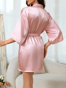 Vue de dos d'un peignoir élégant en satin de soie rose avec ceinture nouée et manches larges