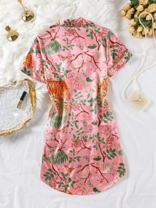 Detail of pink silk pajama shirt dress featuring tiger and floral prints with green piping