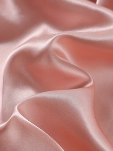 Gros plan sur un tissu satiné rose clair à la texture lisse et au reflet soyeux