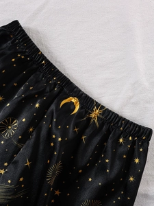 Detail einer Satin-Pyjamahose mit goldenem Mond- und Sternmuster und elastischem Bund