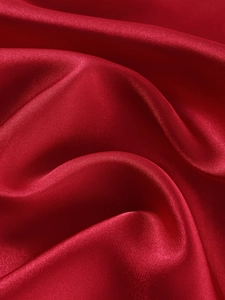 Gros plan sur la texture du satin de soie rouge avec un drapé élégant et brillant