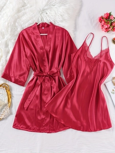 Detail of red satin pajamas set with delicate lace trim and matching belted robe