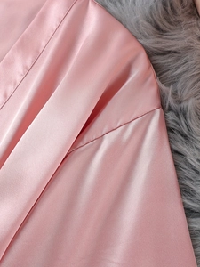 Gros plan du tissu de pyjama en soie rose montrant le satin lisse et les coutures