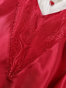Détail de nuisette en satin rouge avec dentelle florale raffinée et décolleté plongeant