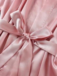 Détail du vêtement de nuit en satin rose montrant la texture de soie et le nœud de taille