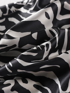 Makro-Detail des abstrakten schwarz-weißen Zebramusters auf glänzender Satin-Stofftextur