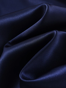 Macro detail of glossy dark blue satin sleepwear fabric showing smooth silk-like texture