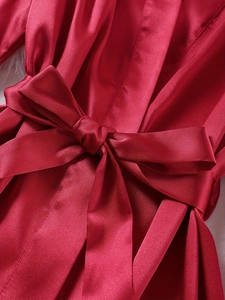 Detailed macro view of the wine red satin robe featuring a large silk bow belt knot