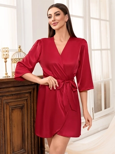 Détail d'un peignoir élégant en satin rouge foncé avec texture soie et ceinture nouée