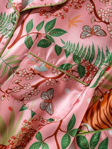 Detail of silk satin nightdress showing floral print, green piping and chest pocket