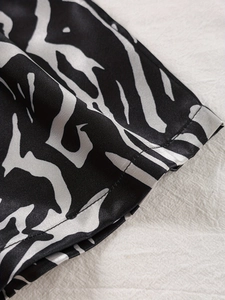 Detaillierte Makroaufnahme von Seiden-Zebra-Stoff und feinen Nähten an einem Satinkleid
