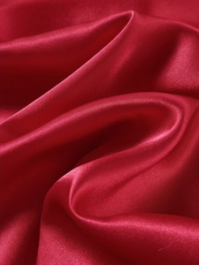 Close-up of luxurious red satin fabric with elegant silk texture and glossy drape