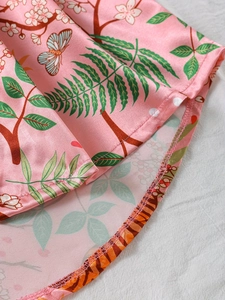 Detail of satin nightdress featuring butterfly prints and precise red hem stitching