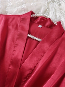Close-up of red satin sleepwear showing smooth texture, size S label, and white lace decor
