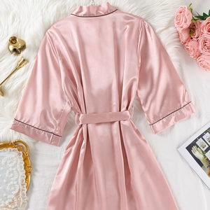 Peignoir en satin rose avec liseré noir sur fond en peluche blanche et roses