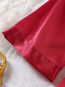 Detail shot of wine red satin fabric with smooth texture and neat hemline stitching