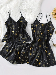 Detail eines schwarzen Satin-Schlafanzugsets mit goldenem Mond- und Sternenmuster