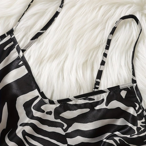 Elegantes Satin-Trägerkleid mit Zebradruck und dünnen Trägern auf weißem Plüsch-Hintergrund