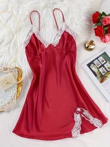 Detail of red satin sleepwear with white lace trim and bow on white faux fur background