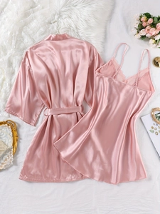 Peignoir en satin rose et nuisette en dentelle sur fond de literie blanche avec roses