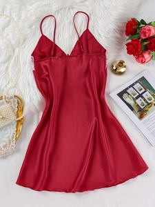 Flat lay of red satin slip dress with white lace details and thin straps on white rug