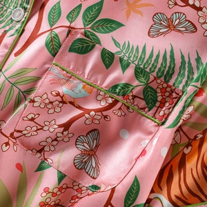 Pink faux silk pajama shirt with nature patterns and green piping detail closeup