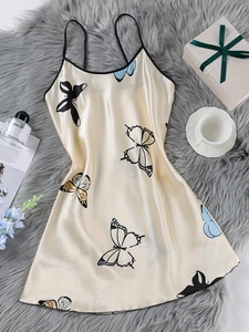 Flat lay of satin chemise with butterfly print on plush carpet with elegant gift props