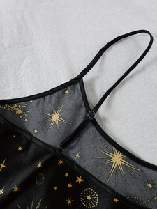 Détail du pyjama en soie noire avec imprimé étoiles dorées et fines bretelles