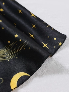 Detail der schwarzen Satin-Schlafanzugoberfläche mit goldenen Mond- und Sternenmustern