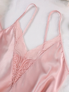 Détail macro du pyjama en satin rose avec décolleté en dentelle fine et texture soyeuse