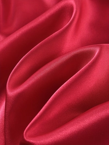 Detailed view of glossy red satin fabric texture and premium silk material draping