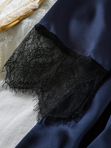 Detail of dark blue satin robe sleeves with delicate black eyelash lace and floral trim