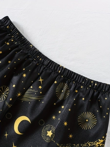 Detail der schwarzen Satin-Schlafanzughose mit Gummizug und goldenem Sternmuster