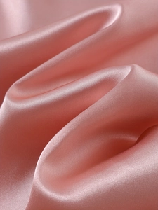 Macro di tessuto in raso rosa con texture lucida e setosa e caduta dei drappeggi