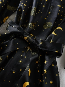 Détail du peignoir en satin noir avec motifs célestes dorés et ceinture en soie