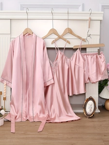 Détail d'un ensemble de nuit en satin rose avec dentelle blanche et passepoils noirs contrastés