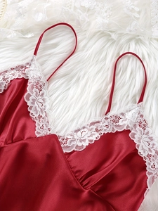 Close-up of red satin nightgown with exquisite white floral lace trim on soft plush carpet