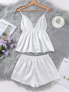 Detailansicht eines weißen Satin-Pyjama-Sets mit floraler Spitze und V-Ausschnitt