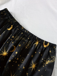 Détail de la taille élastique d'un pyjama en satin noir avec motifs lunes dorées