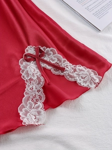 Detail of red satin sleepwear featuring white lace hem and a decorative ribbon bow