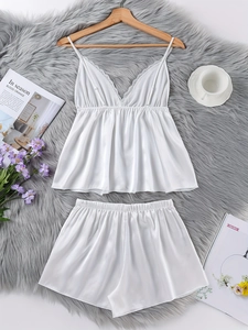 Nahaufnahme des weißen Seidensatin-Pyjama-Sets mit Spitzen-V-Ausschnitt auf einem Teppich