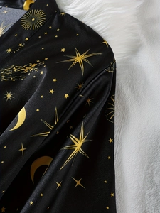 Détail d'un peignoir en satin noir avec motifs dorés célestes de lune et d'étoiles