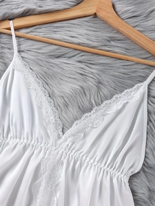 Detail eines weißen Satin-Schlafanzug-Oberteils mit Spitze und V-Ausschnitt