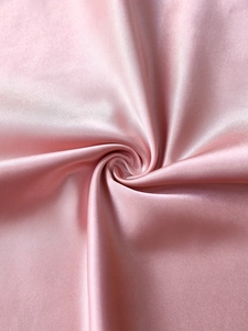 Vue macro du tissu satin rose clair montrant un éclat perlé et une texture soyeuse