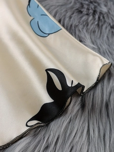 Detailed view of silky satin fabric with abstract floral prints and neat stitching